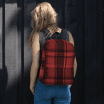 A woman wearing a Backpack in Celtic Red Highland Plaid, can hold up to a 15" Laptop, or Tablet, many pockets for more, Padded Shoulder Strapssturdy, Water Resistant.