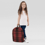 A little girl holding a Backpack in Celtic Red Highland Plaid, can hold up to a 15" Laptop, or Tablet, many pockets for more, Padded Shoulder Strapssturdy, Water Resistant.