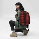 A woman squatting down with a Backpack in Celtic Red Highland Plaid, can hold up to a 15" Laptop, or Tablet, many pockets for more, Padded Shoulder Strapssturdy, Water Resistant.