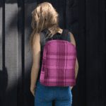 A woman wearing a Backpack Celtic Fucia Pink and Burgundy and Black Highland Plaid, can hold up to a 15" Laptop, or Tablet, many pockets for more, Padded Shoulder Straps.