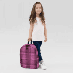 A little girl wearing the Backpack Celtic Fucia Pink and Burgundy and Black Highland Plaid, can hold up to a 15" Laptop, or Tablet, many pockets for more, Padded Shoulder Straps.