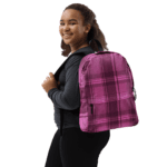 A girl wearing a Backpack Celtic Fucia Pink and Burgundy and Black Highland Plaid, can hold up to a 15" Laptop, or Tablet, many pockets for more, Padded Shoulder Straps.