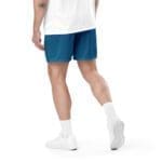 Man in blue shorts walking in white sneakers.