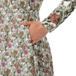 Woman in a floral dress with hand in pocket.