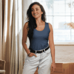 Woman in blue tank top and jeans smiling.