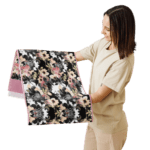 Woman holding floral fabric with pink trim.