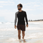 Man in patterned rash guard on beach.