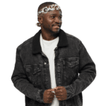 Man in denim jacket and bandana smiling.