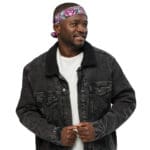 Man in black denim jacket with floral headband.