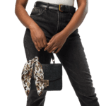 Woman in jeans holding a black purse.